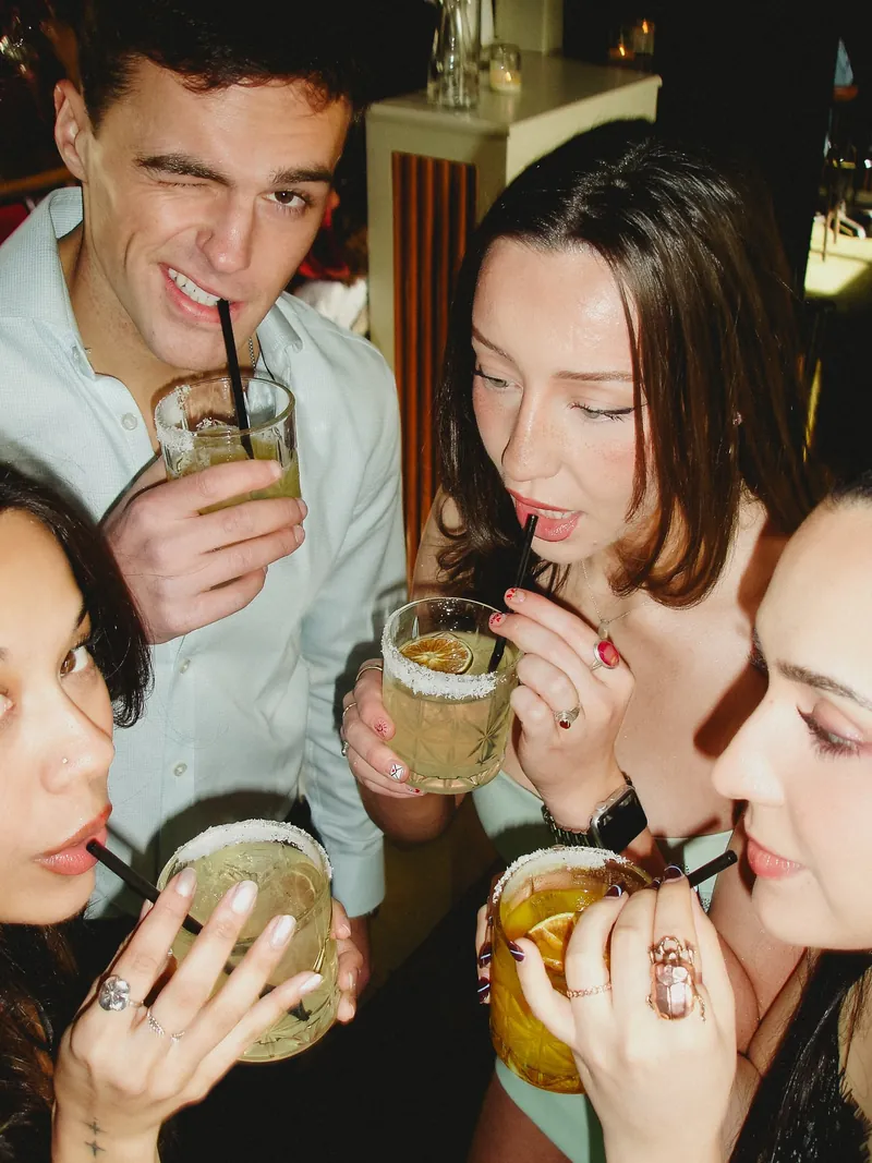 Three women and a man drinking margaritas with salt rims in a circle at Avenida