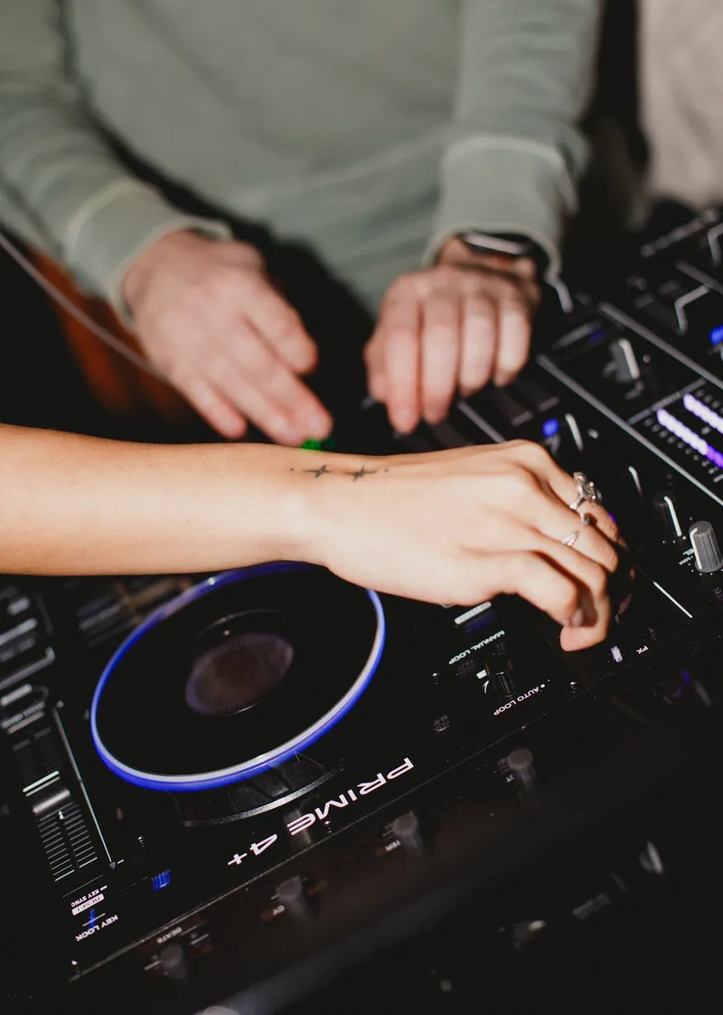 Close up of DJ decks with hands adjusting the turntable