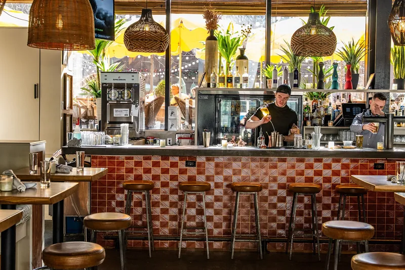 Indoor bar with two bartenders making drinks at Avenida near Penn Station