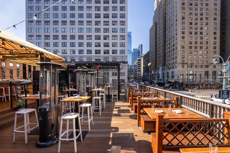 Seating area on Avenida’s rooftop with large buildings on 8th Avenue in the background