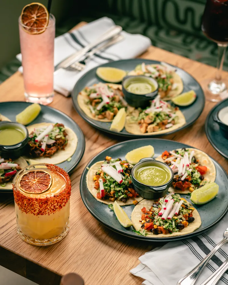 Square table with three plates of tacos at Avenida